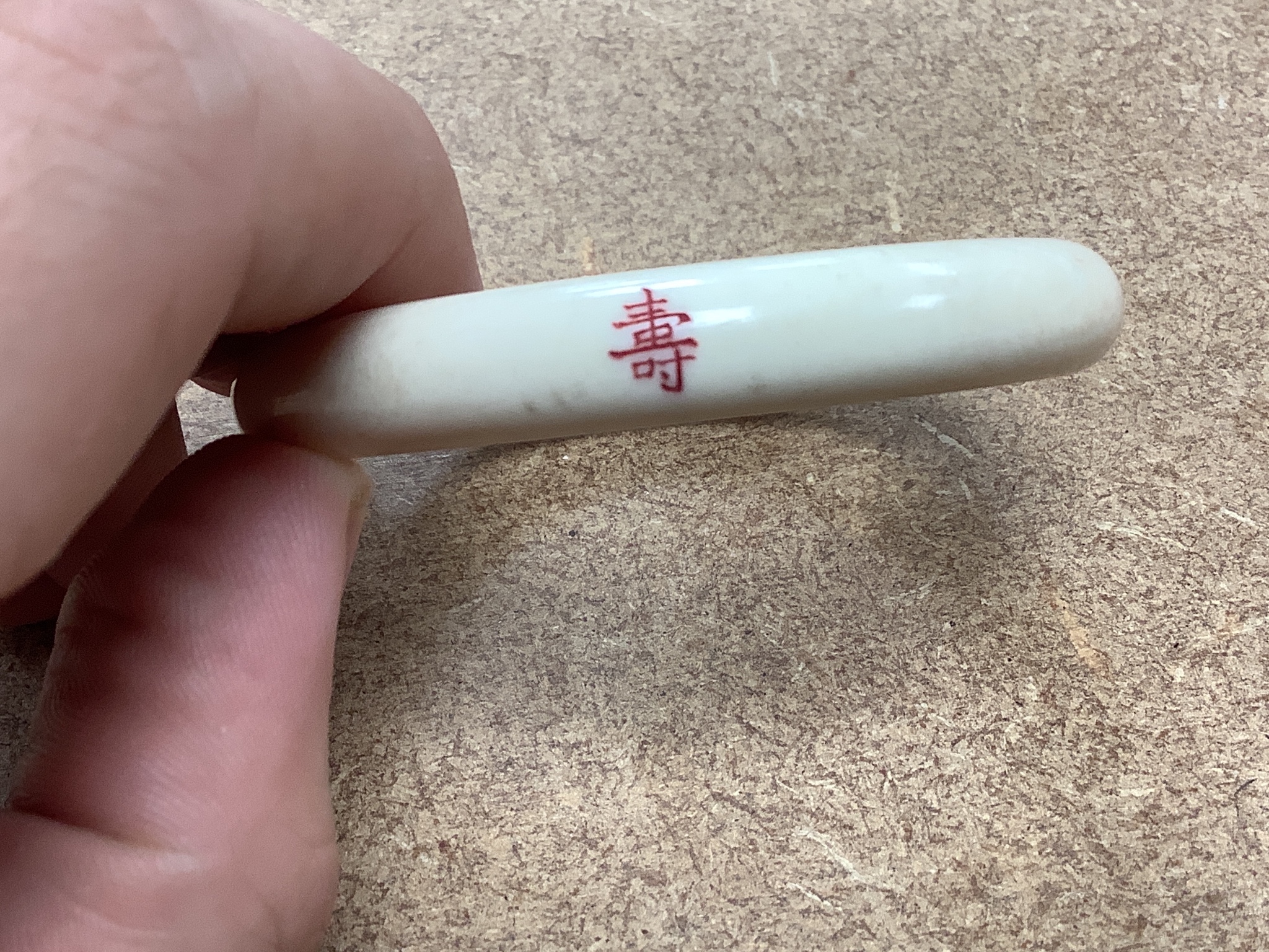 A 19th century panelled mother of pearl box together with a Chinese carved peach stone, a Chinese ivory bangle and a small worked bone multi-tool